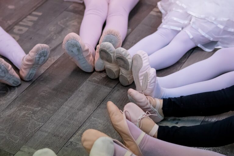 A young dancer receives encouragement from a parent while tying dance shoes backstage before a performance.