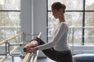 Young ballet dancers practicing at a barre in a bright, modern dance studio.